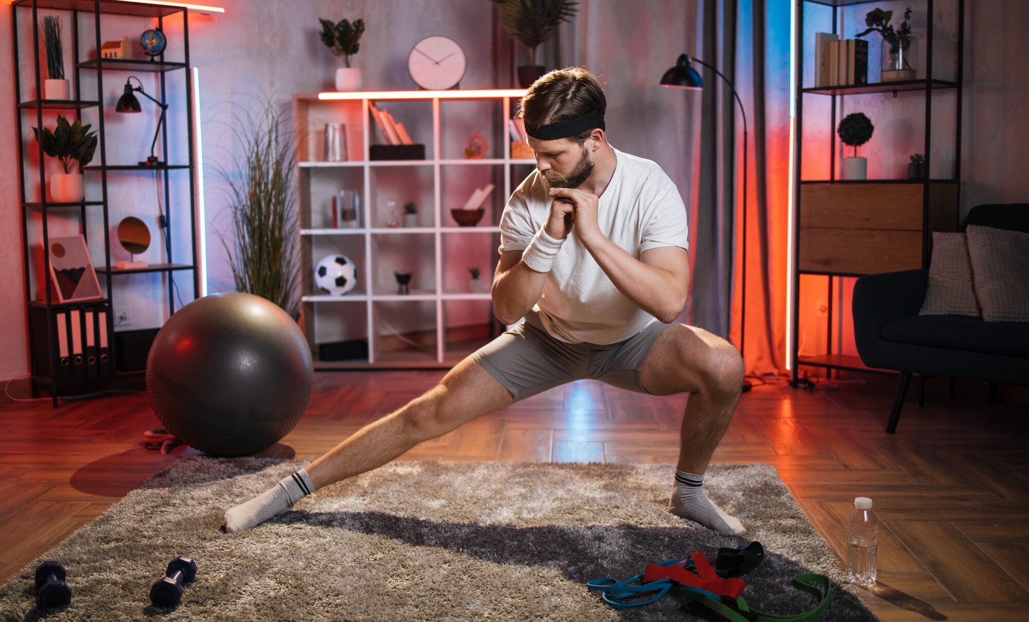 Man in sportswear doing side lunges sports exercises at home